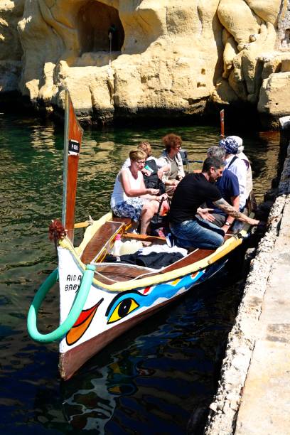 Tourists on a Dghajsa, Malta. Passengers on board a traditional Maltese Dghajsa water taxi in an inlet alongside Fort San Angelo, Vittoriosa, Malta, Europe. coconut crab stock pictures, royalty-free photos & images