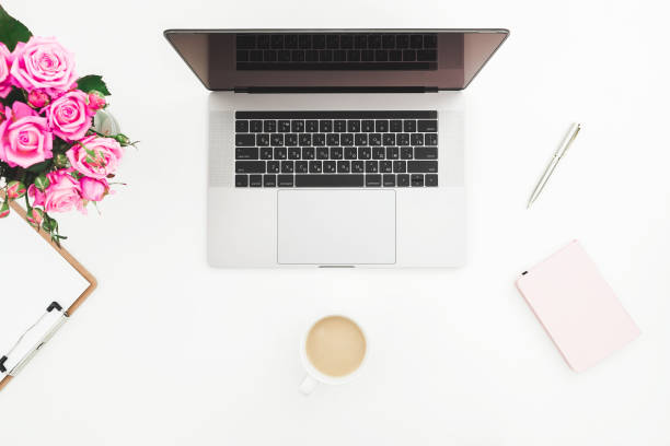 istock Desk with female workspace - laptop, pink roses, coffee mug, pink diary on white background. Flat lay. Top view. 920412978