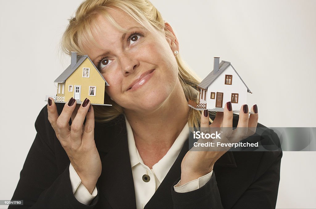 Contemplativo mujer sostiene dos pequeño casas del modelo - Foto de stock de Contemplación libre de derechos