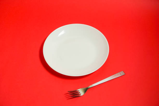 istock a white dish and a folk and a knife. restaurant image. red background. 920424226