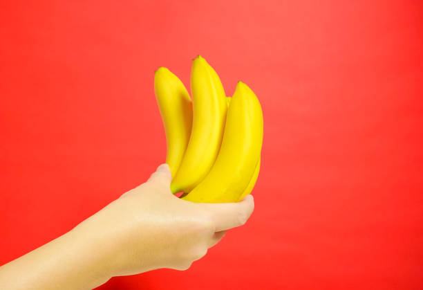 istock The banana which is held by a hand. red background 920427614