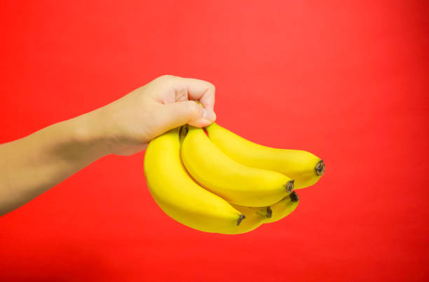 istock The banana which is held by a hand. red background 920427622