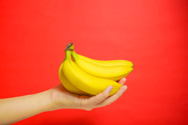 istock The banana which is held by a hand. red background 920427624