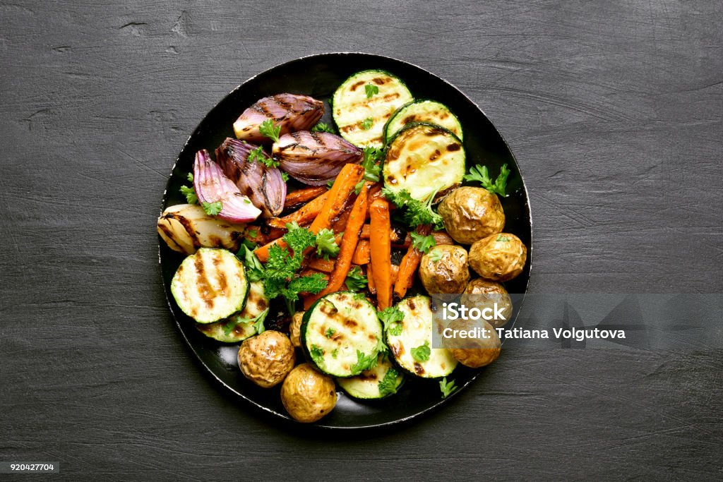 Roasted vegetables Baked vegetables in plate on black background. Top view, flat lay Vegetable Stock Photo