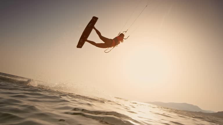 SLO MO Female kiteboarder doing a jump at sunset