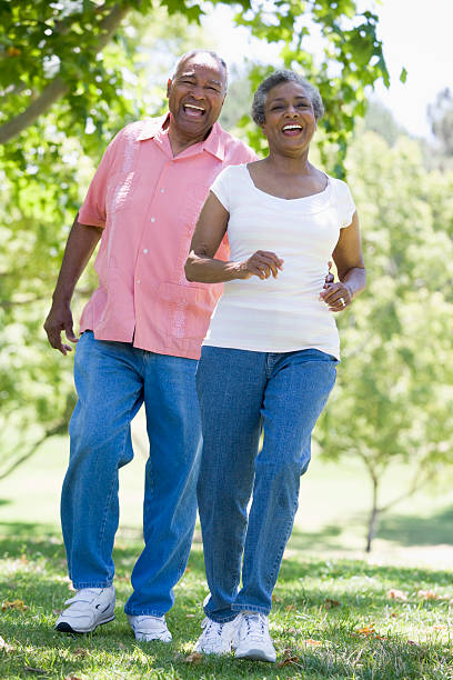 coppia senior divertendosi nel parco - chasing women men couple foto e immagini stock