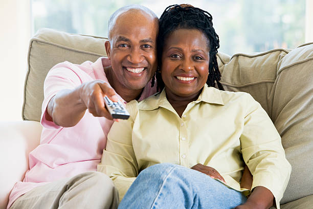 istock Smiling couple together on a couch picking what to watch 92044520