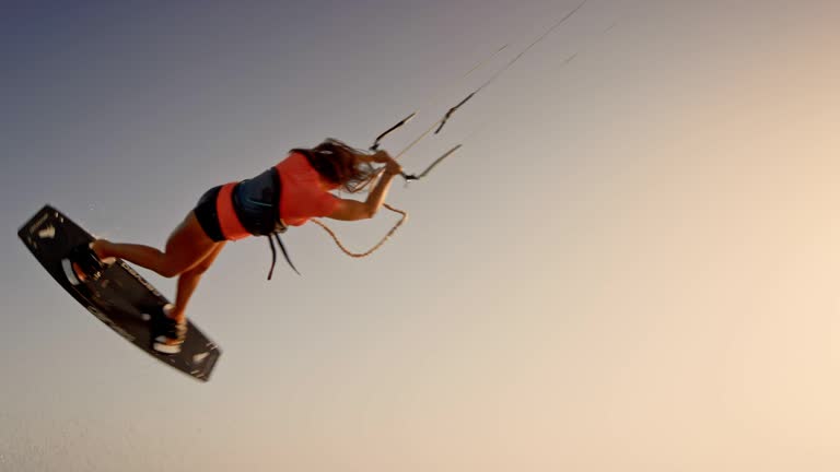 SLO MO Female kiteboarder jumping and turning at sunset