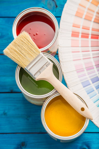 Paint cans color palette, cans opened with brushes on blue table