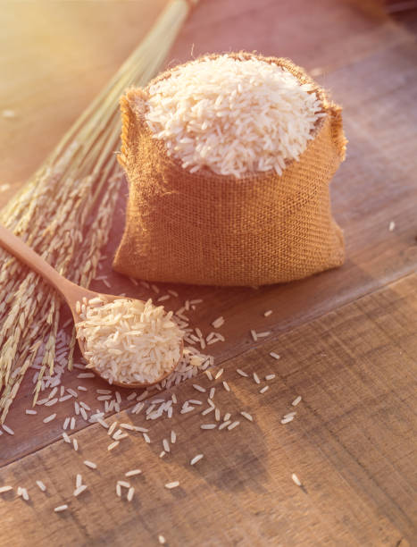 istock Thai jasmine rice in spoon and small sack on wooden table background 920459270