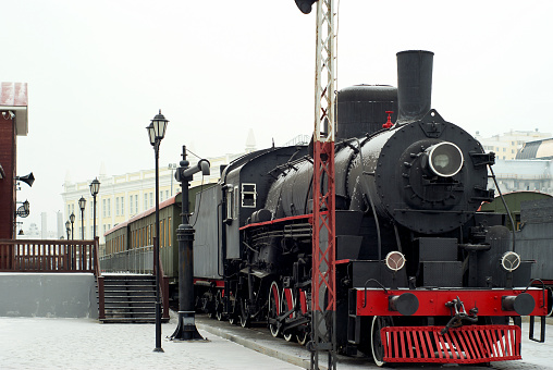 vintage steam locomotive with wagons standing at the railway station in winter