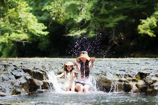Mother and daughter are playing water in a mountain stream