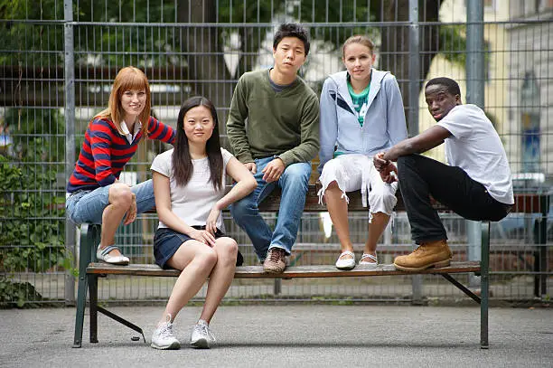 Photo of Five diverse young people sitting on a bench