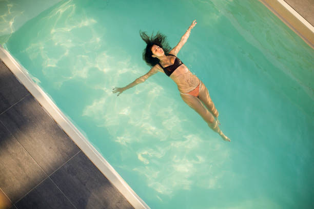 istock Woman in bikini  floating on water in the pool 920465398