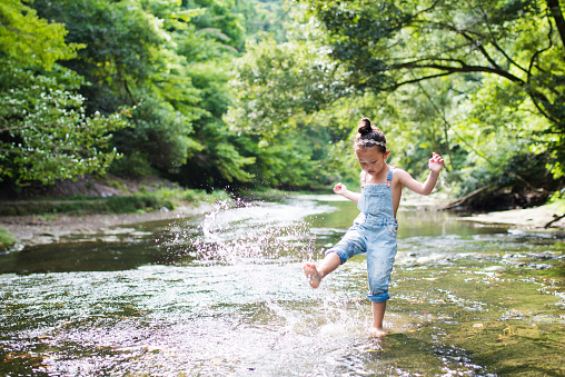 Little girl is playing in a stream in the forest