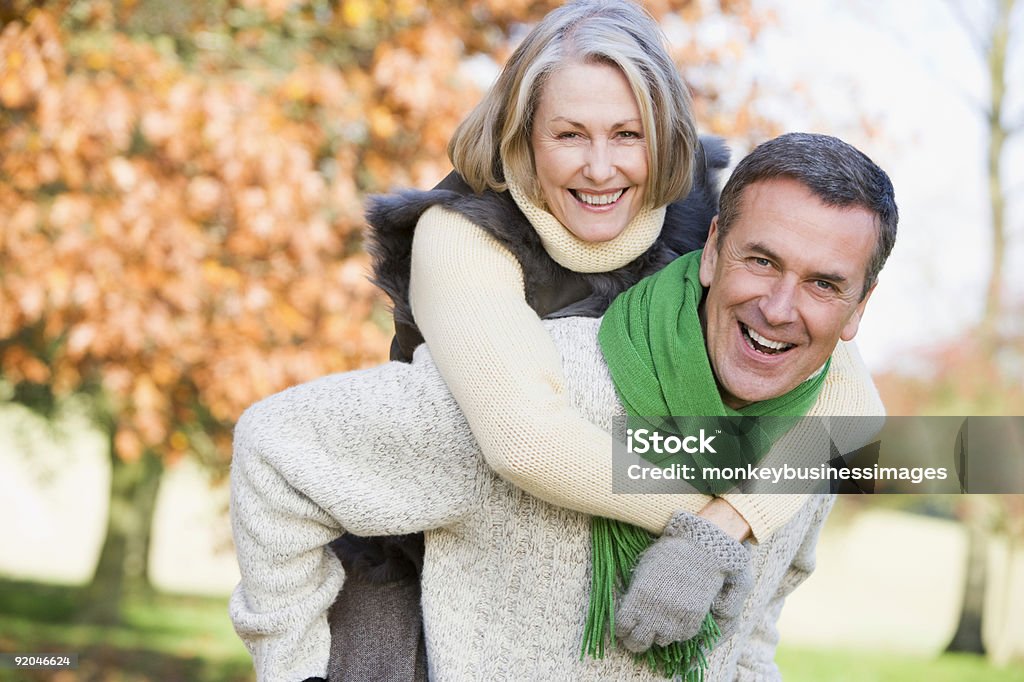 Senior man giving woman piggyback ride  Mature Couple Stock Photo