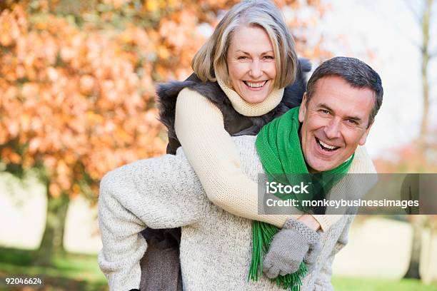 Senior Man Giving Woman Piggyback Ride Stock Photo - Download Image Now - Mature Couple, Autumn, Exercising
