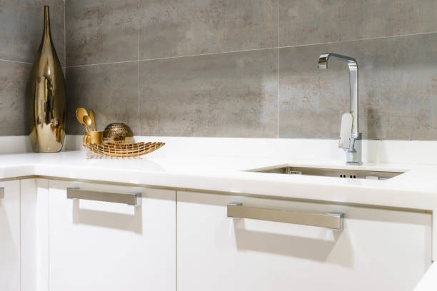 istock Modern white kitchen countertop with white granite. Custom counter with stainless steel sink and faucet. 920477684