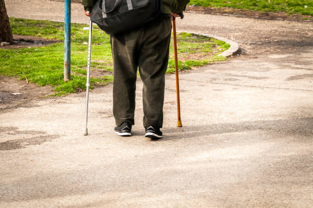 istock Old man walk alone and depressed down the street with two walking stick or cane view from back 920478544