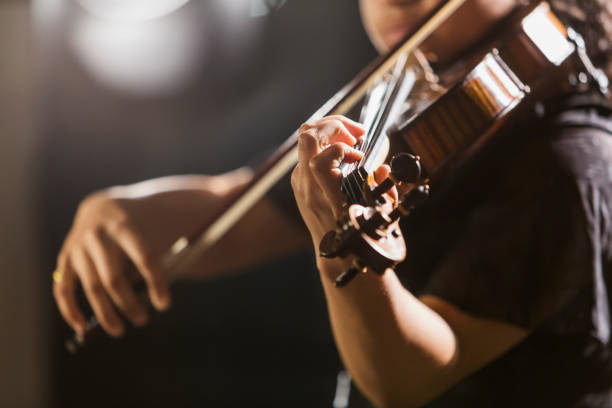 Mixed race teenage girl playing the violin Close-up of a mixed race teenage girl, 15 years old, playing the violin in concert. The focus is on her hand.  She is African-American, Caucasian and Hispanic. solo performance stock pictures, royalty-free photos & images