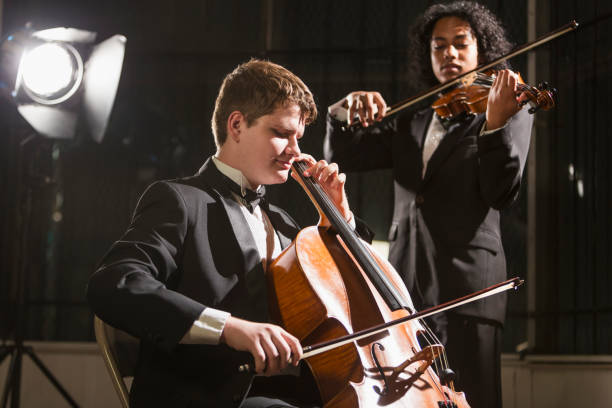 Teenage boys playing double bass and violin in concert Two multi-ethnic teenage boys playing string instruments in an orchestra. The main focus is on the 15 year old boy playing the double bass. symphony orchestra photos stock pictures, royalty-free photos & images