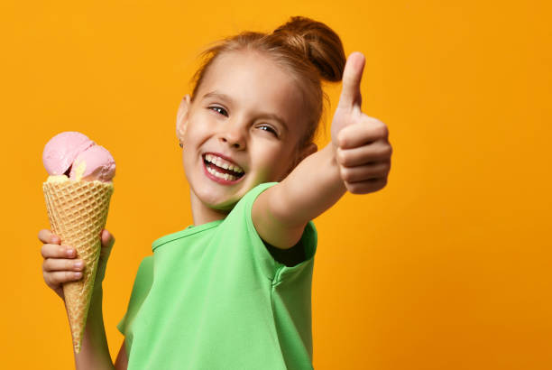 Pretty baby girl kid hold banana and strawberry ice cream in waffles cone stock photo