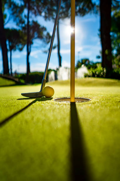 istock Mini Golf yellow ball with a bat near the hole at sunset 920496420
