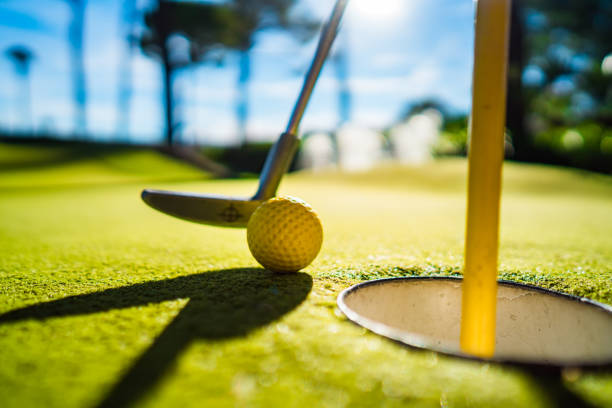 istock Mini Golf yellow ball with a bat near the hole at sunset 920496426