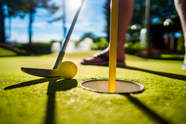 istock Mini Golf yellow ball with a bat near the hole at sunset 920496468