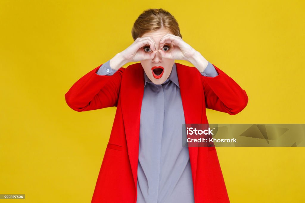 Mulher cabeça vermelha na roupa vermelha olhando em binóculos muito longe. - Foto de stock de Binóculos royalty-free