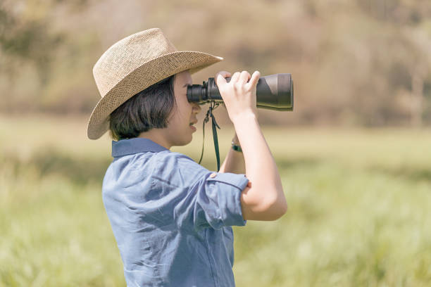 istock Woman wear hat and hold binocular in grass field 920497686