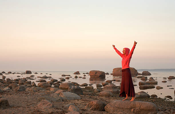 istock happy woman raising hands on seashore at sunset 92050159