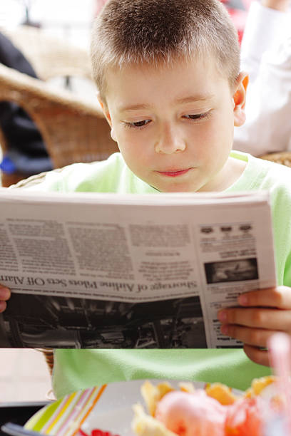 istock Young boy intently reading the newspaper 92051163