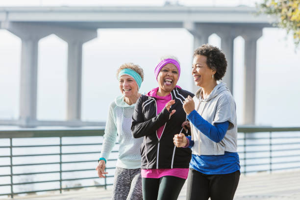 istock Three mature women power walking together on waterfront 920524678