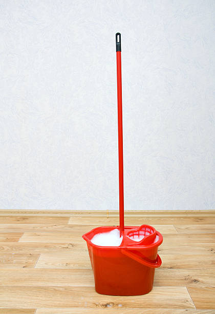 Red mop in a plastic bucket on floor stock photo