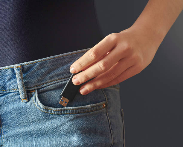 Young woman pushing usb flash drive into a jeans pocket