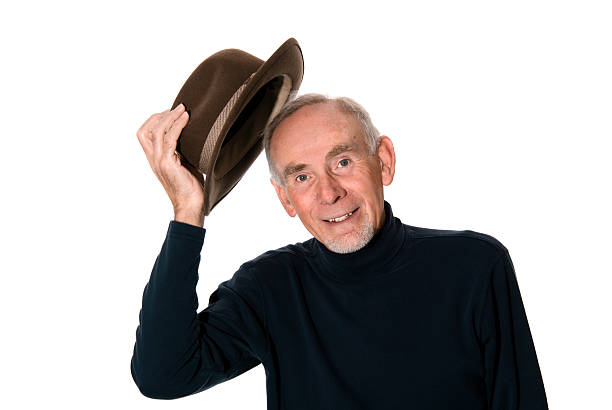 A senior man taking off his hat in greeting Smiling senior man doffing his hat in polite greeting undressing stock pictures, royalty-free photos & images