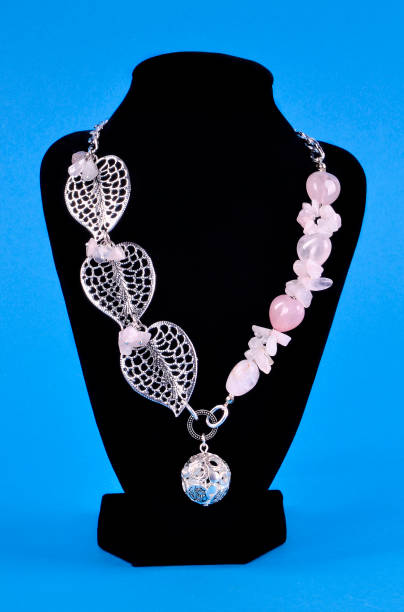 istock silver necklace with pink quartz stones on a black stand on a blue background 920542018
