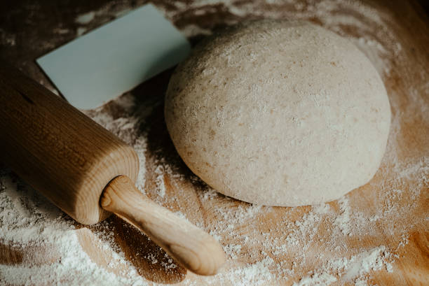 istock Whole wheat pizza dough shaped into ball on floured wooden background 920549826