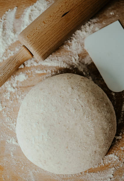 istock Whole wheat pizza dough shaped into ball on floured wooden background 920550232