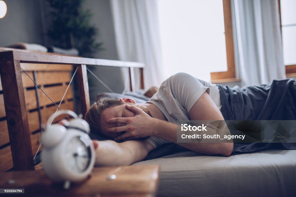 Wake Up Early Sleeping man disturbed by alarm clock early in the morning Waking up Stock Photo