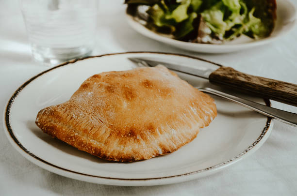 pizza calzone zamknięta pizza z szynką i serem nadzieniem na białym talerzu z zieloną sałatą sałatką - pizza pastry crust stuffed cheese zdjęcia i obrazy z banku zdjęć