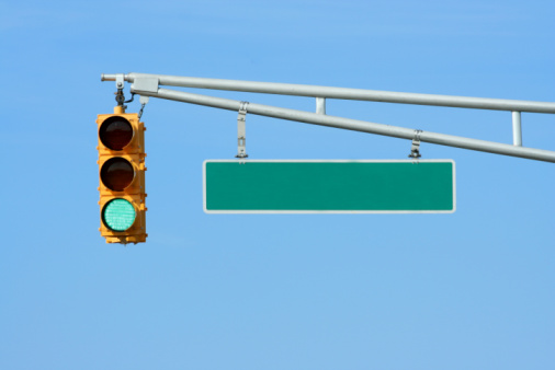 Simple image of a modern traffic light, showing green, on a street in downtown Boston.
