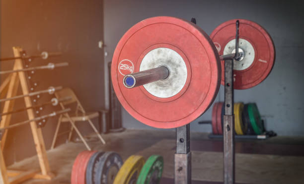 Weightlifting Gym A barbell loaded with weights sits above an Olympic style platform. clean and jerk stock pictures, royalty-free photos & images