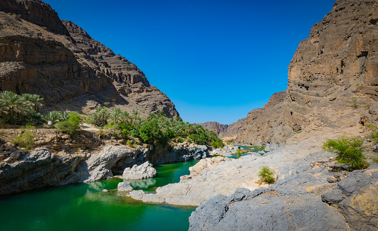 Oman landscape with mountains, green water and blue sky.
