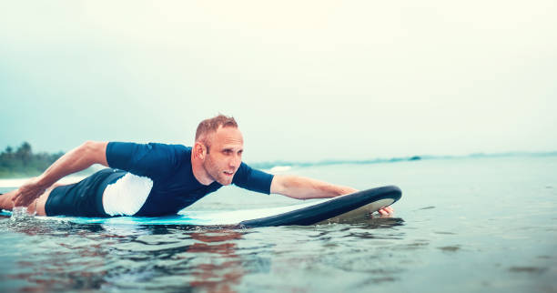 istock Man padding to line up on the surf board 920620068