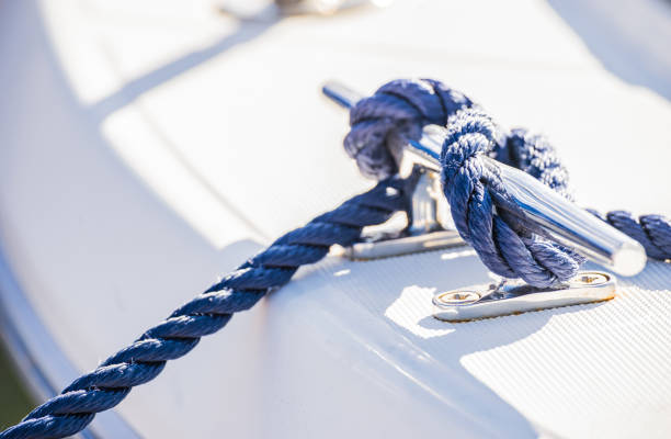 Blue nautical rope is knotted on boat cleat Detail view of blue nautical rope cleat on boat deck mooring line stock pictures, royalty-free photos & images