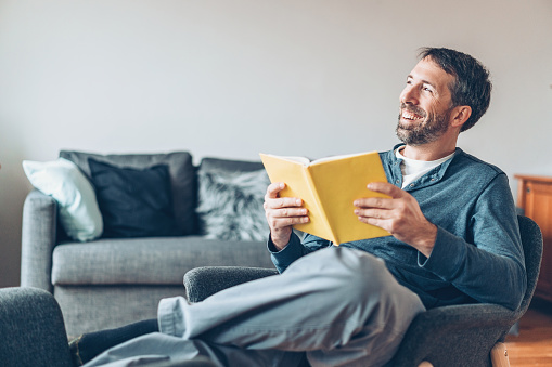 Smiling middle aged man reading a book at home
