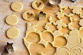 Preparation of traditional Linzer Christmas cookies - cutting out star and heart shapes from rolled out dough