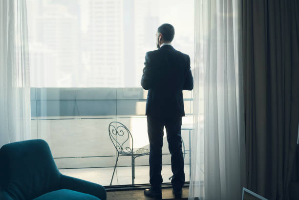 istock Businessman looking through window of hotel 920645554
